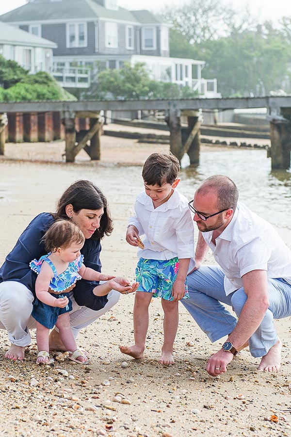 Family of 4 at the beach looking at a shell by Nantucket Family Photographer