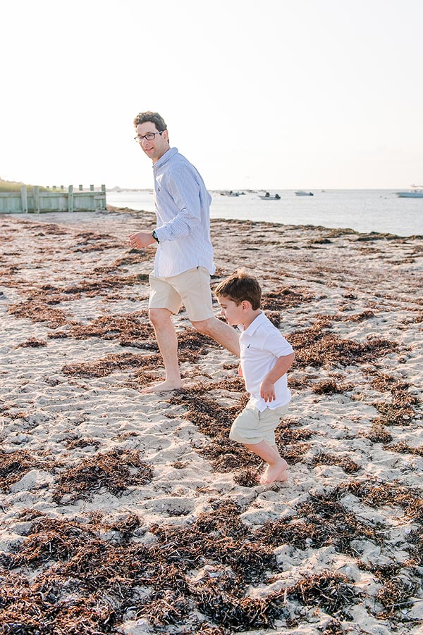 Little boy running on beach with Dad by Nantucket Family Photographer