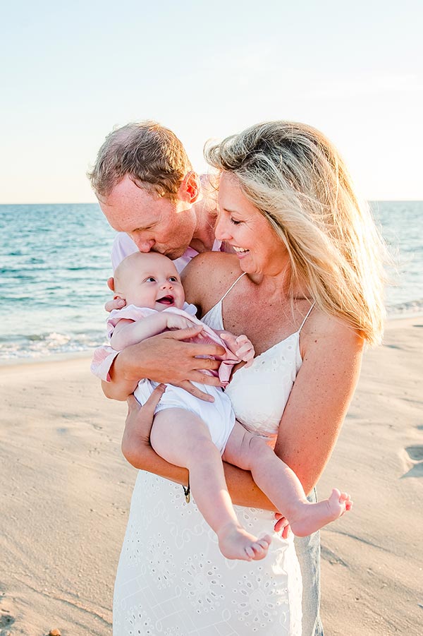 Parents smiling at baby on the beach by Nantucket Family Photographer